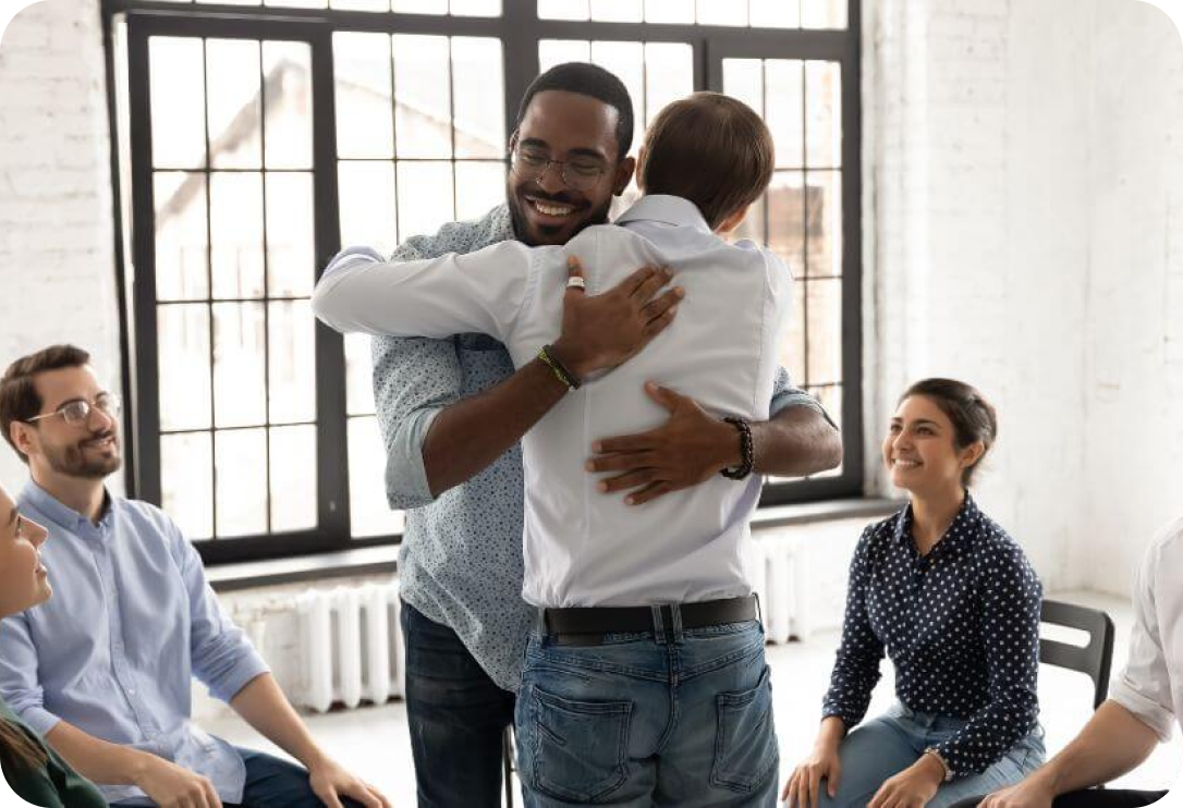 Two men hugging in the middle of a group circle