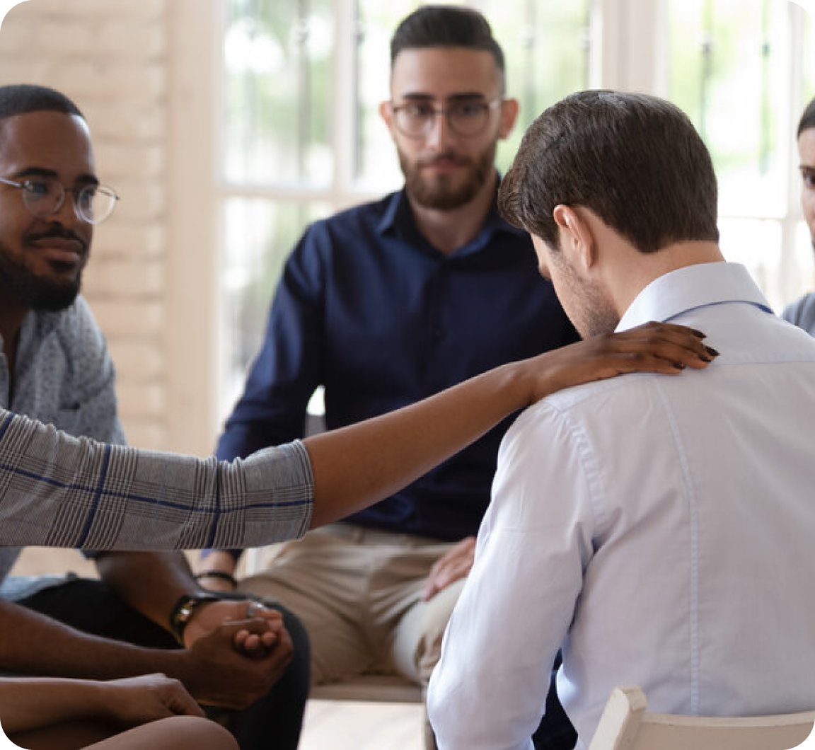 Group of people comforting a man